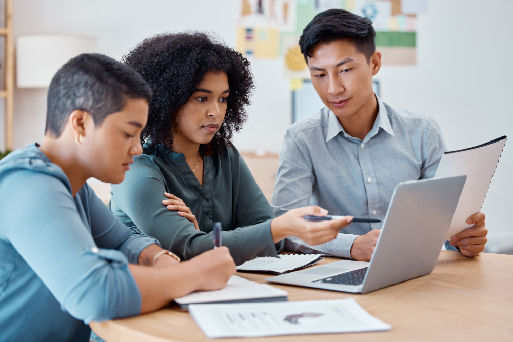 two female presenting people of color and a male person of color looking at a laptop together