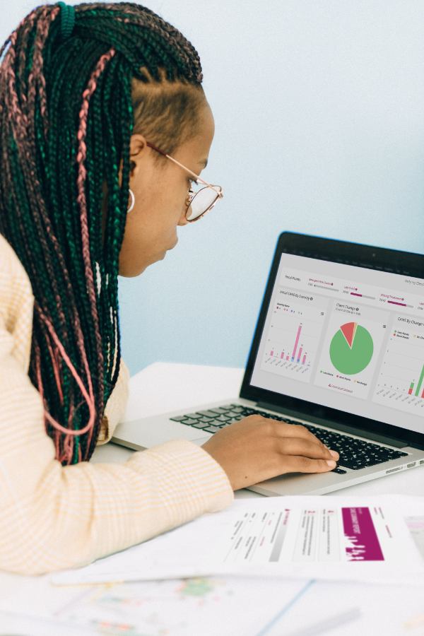 black woman with braids looking at graphs and charts on a laptop